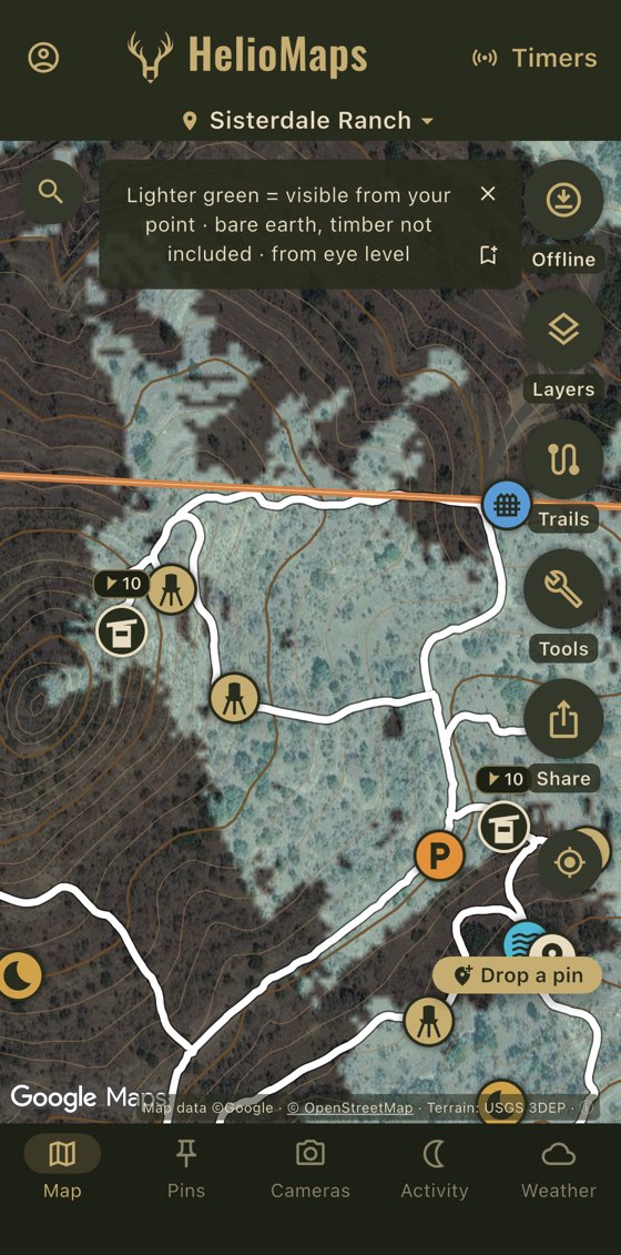 Line of sight on a ranch map over satellite imagery with contour lines, trails and stand pins: the ground visible from a chosen point is marked in pale green, with the app's note that it is bare earth, timber not included, from eye level.